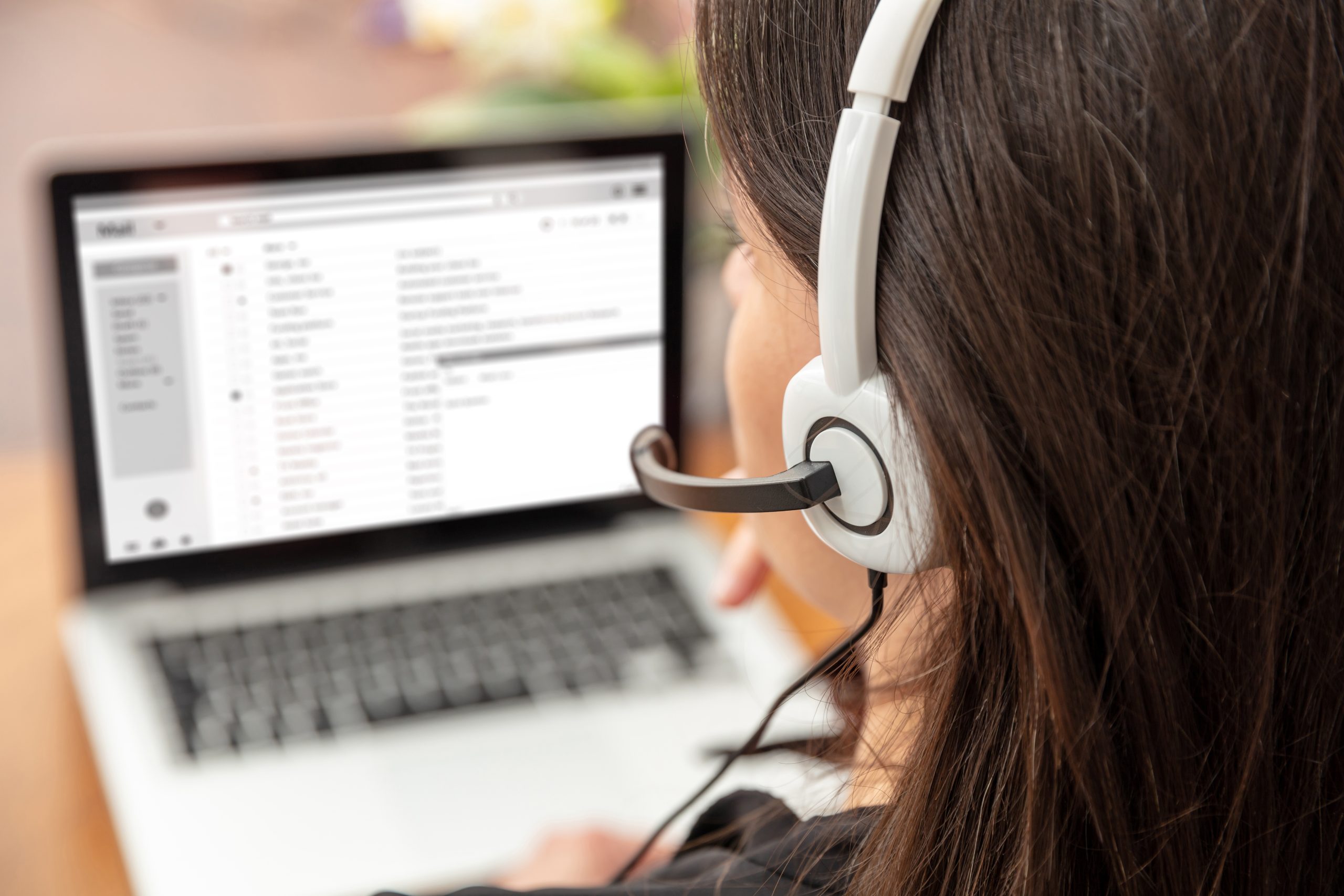 Home office, customer support, help desk concept. Woman with headset work on a laptop Managed IT Service Provider